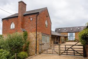 an old brick building with a gate in front of it at Grooms Cottage in Weedon Bec