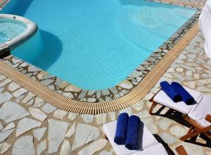 une piscine avec deux chaises longues et une piscine dans l'établissement Boutique apart-hotel Galini, member of the best small hotels in Greece, Adults only, à Volímai