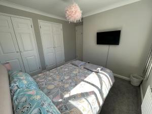 a bedroom with a bed and a flat screen tv at City Retreat 3 Bed House with King, Double and Single in Southampton