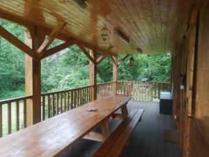 a wooden porch with a wooden bench on a deck at Au petit bonheur in Le Tholy