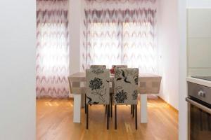 una mesa y sillas en una cocina con cortinas rosas en Sea Point apartment Korda, en Budva