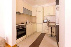 una cocina con armarios blancos y una silla. en Sea Point apartment Korda, en Budva