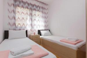 2 camas en una habitación con paredes rosas y blancas en Sea Point apartment Korda, en Budva