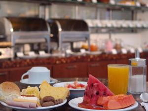 een tafel met borden met voedsel en sinaasappelsap bij Coqueiros Express Hotel in Maceió