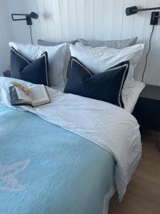 a bed with a book and pillows on it at Lykkeli in Risør +2 photos