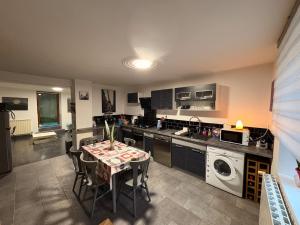 a kitchen with a table with chairs and a washing machine at La Maison Forestière in Liverdun