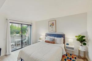 a white bedroom with a bed and a balcony at Mi Hermosa in Palm Springs