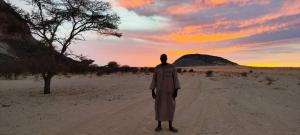 a man walking down a dirt road in the desert at Transit in Nouakchott