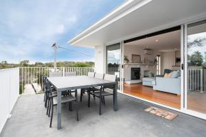 patio con mesa y sillas y sala de estar. en Family Beach Retreat With Heated Pool Blairgowrie, en Blairgowrie