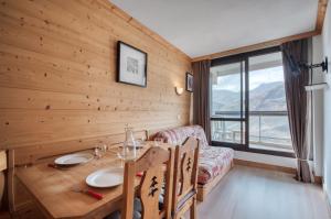 Un comedor con una mesa y un sofá. en Appartement N° 46, en Les Menuires
