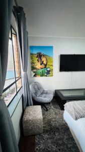 a room with a bed and a chair and a television at HOPE-always in Cape Town