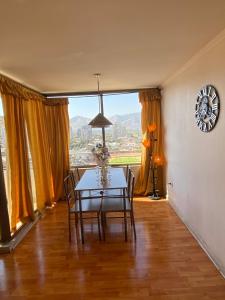 a dining room with a table and chairs and a large window at Departamento Impecable in Santiago