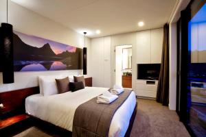 a hotel room with a large bed and a television at Mountain Lake Vista 3 Bedroom in Queenstown