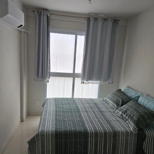 a bedroom with a bed with a plaid blanket and a window at Casa de Praia em Jacaraipe soneto do Mar in Serra