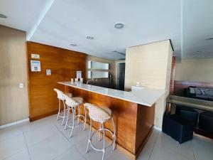 Una cocina con encimera y taburetes en una habitación. en Apartamento Porto Real - Mangaratiba, en Mangaratiba