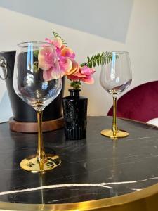 two wine glasses and a vase with flowers on a table at Relax Room proche PARIS Porte de Versailles in Malakoff