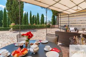una mesa con fruta y un jarrón de flores. en Villa Le Tortore privata lusso piscina relax Siena, en Siena
