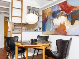 a dining room table with chairs and a painting on the wall at 6 person holiday home in Løkken-By Traum in Løkken