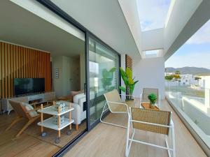 ein Wohnzimmer mit Glasschiebetüren und einem TV in der Unterkunft San José Suites 3 Hab, Piscina, solárium y WiFi in Almería