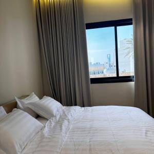 a bed with white sheets and pillows in front of a window at شقه فاخره وسط حي السليمانيه in Riyadh