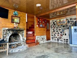 a living room with a stone fireplace and a tv at Cabaña Bella Vista in Pasto