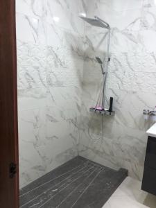 a bathroom with a shower with white marble walls at Appartement marina beach f5 n6 in M'diq +22 photos