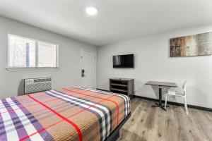 a bedroom with a bed and a desk and a computer at Southern Suites Forest Park in Forest Park