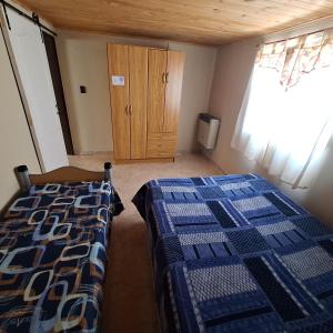 Un dormitorio con dos camas y un armario de madera. en Hospedaje Calel, en Gobernador Gregores