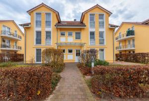 a large yellow house with a pathway in front at Schloonseevillen FeWo 17 in Bansin
