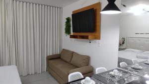 a living room with a couch and a television on a wall at Flat Studio in João Pessoa