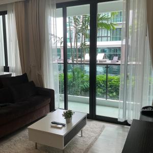 a living room with a couch and a large window at Royal Lee Phuket Condominium Airport in Ban Bo Han