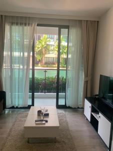 a living room with a couch and a tv and a table at Royal Lee Phuket Condominium Airport in Ban Bo Han +18 photos