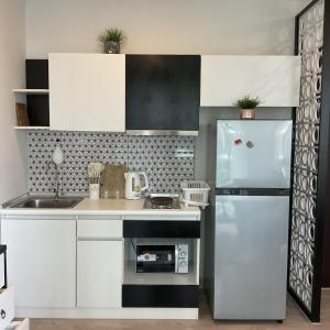 a kitchen with white cabinets and a refrigerator at Royal Lee Phuket Condominium Airport in Ban Bo Han