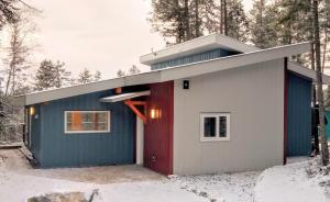 a small house with a red door in the snow at Valley Edge Lodge in Golden