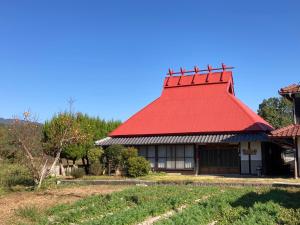 Yasudaもりのもむ Morinomomu Guest House in Mitsuo的红色屋顶建筑,有红色屋顶