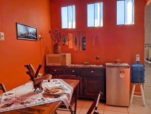 a kitchen with orange walls and a table and a microwave at Pousada Angatu, microcasa em BH in Belo Horizonte