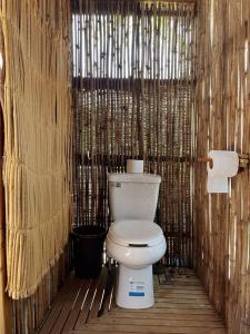 a bathroom with a toilet in a bamboo wall at Hostal Onahu Chacahua in Guayabas