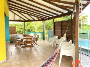 a patio with chairs and a table and a hammock at Kya's Bungalow - Proche des plages in Le Marin