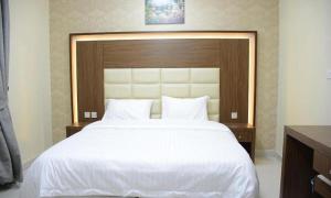 a bedroom with a large white bed with a wooden headboard at تراس للشقق الفندقية in Dammam +6 photos