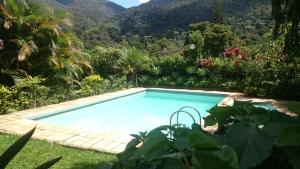 a swimming pool in a garden with mountains in the background at Casa de Araras in Araras Petropolis