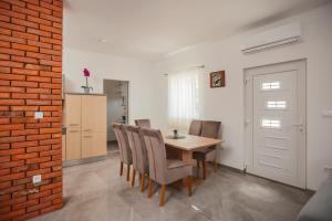 ein Esszimmer mit einem Tisch, Stühlen und einer Ziegelwand in der Unterkunft Holiday house with a parking space Gornji Prolozac, Zagora - 24024 in Gornji Proložac + 4 Fotos