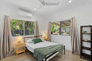 a bedroom with a bed and two large windows at 4 Bedroom House at Holloways Beach in Holloways Beach +11 photos