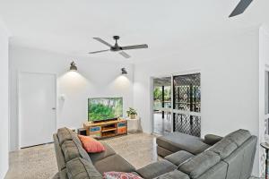 a living room with a couch and a tv at 4 Bedroom House at Holloways Beach in Holloways Beach