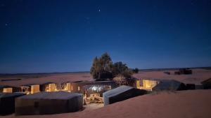 a group of tents in the desert at night at Nomada Desert Camp in Merzouga