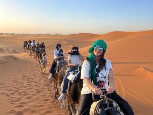 a group of people riding camels in the desert at Soul Dunes Luxury Camp in Merzouga