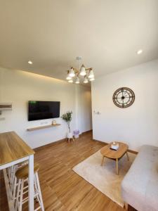 a living room with a couch and a clock on the wall at 19 House in Ban Khlong Pleo