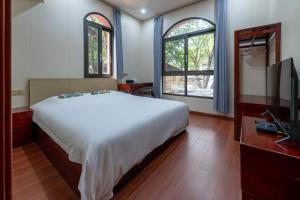 a bedroom with a large white bed and a television at Kaibu Courtyard Superior Apartment, Changjiang Cable Car Nanbin Road, Chongqing in Chongqing