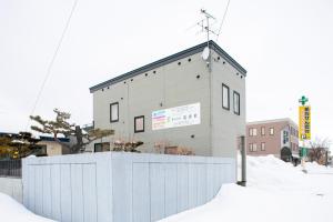 a building with a white fence in the snow at GuestHouse Le Repos in Bihoro