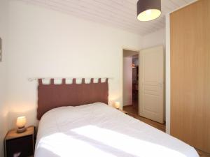 1 dormitorio con 1 cama grande con sábanas blancas y luces en Bel appartement T3 avec garage privé, à 200m du centre du Mont-Dore, 6 couchages, animaux acceptés - FR-1-415-43, en Le Mont-Dore