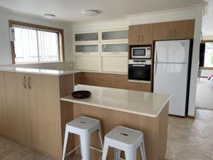 a kitchen with a counter and a refrigerator and stools at Drift at Harrington in Harrington +7 photos